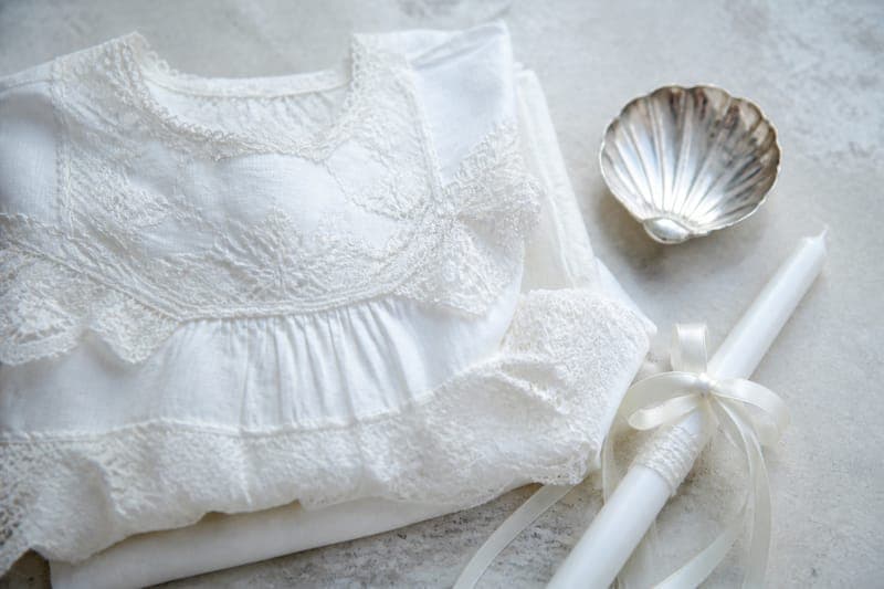 Folded lace christening gown with a silver shell and candle