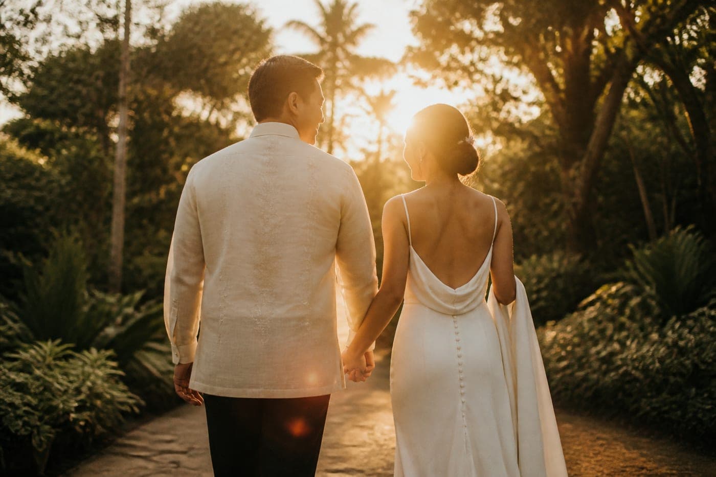 Andrea and Miguel walking a garden path at golden hour