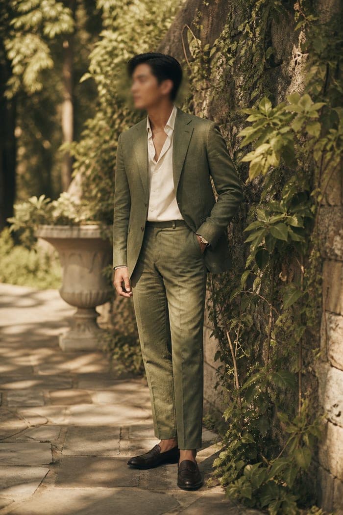 Guest in a moss green linen suit beside a garden wall